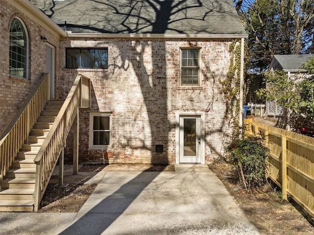 back of property featuring a shingled roof, stairs, and brick siding