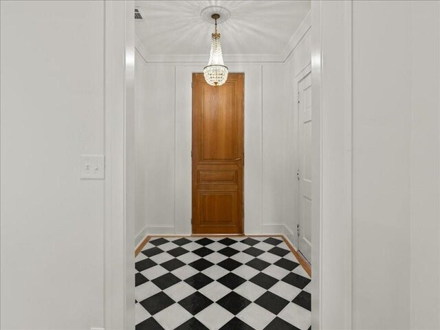 hall featuring a chandelier, a decorative wall, and tile patterned floors