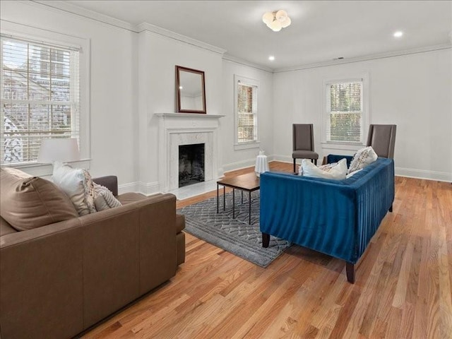 living room with light wood-style floors, ornamental molding, and a high end fireplace