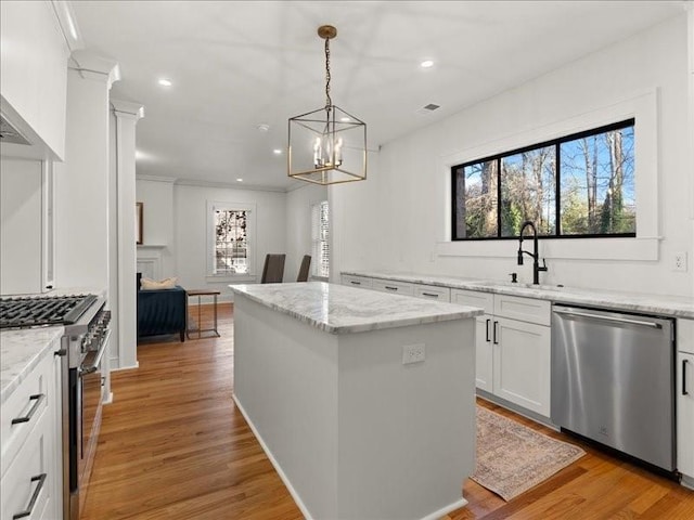 kitchen featuring stainless steel appliances, light wood finished floors, a sink, and a center island