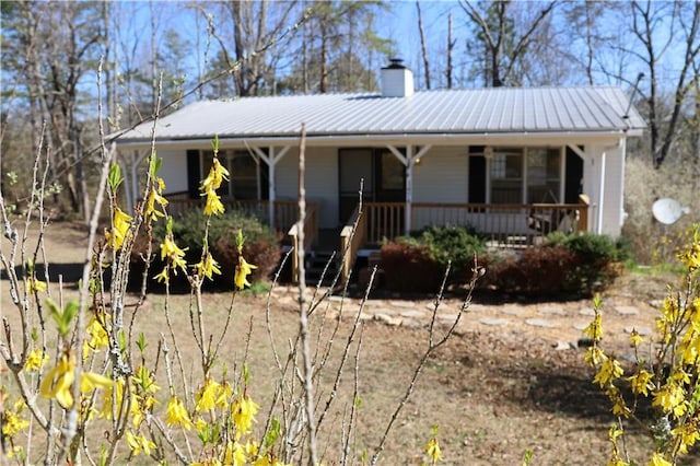 view of front of property featuring a porch, a chimney, and metal roof