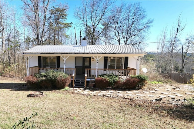 view of front of home featuring metal roof, a porch, and a chimney