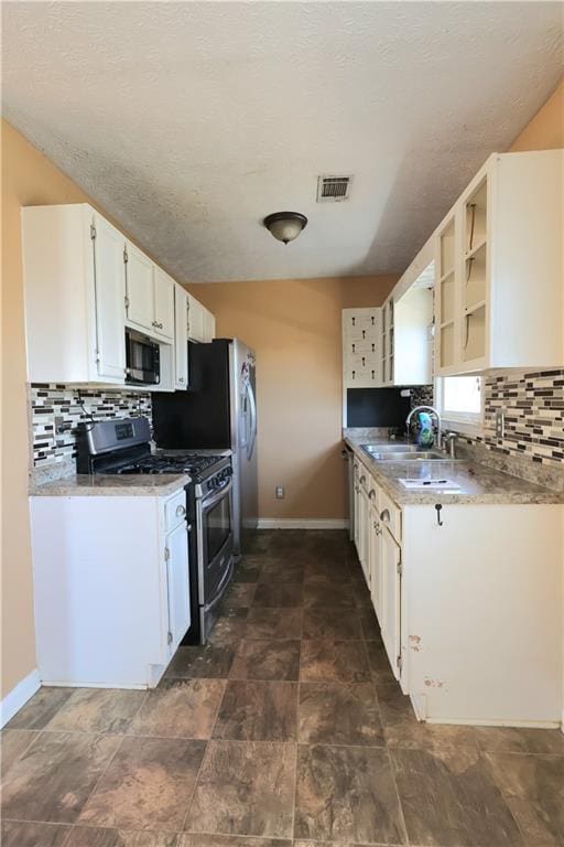 kitchen with visible vents, a sink, stainless steel appliances, white cabinetry, and backsplash