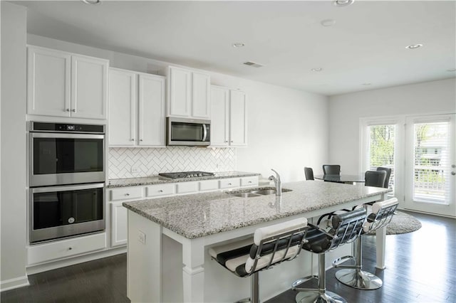 2649 Ogden Trl, Buford, GA 30519 - kitchen with stainless steel appliances, a sink, a kitchen island with sink, white cabinets, and dark wood finished floors