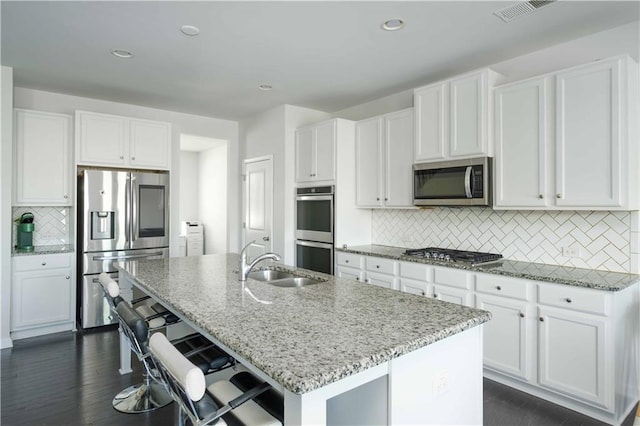 2649 Ogden Trl, Buford, GA 30519 - kitchen featuring appliances with stainless steel finishes, a sink, decorative backsplash, light stone counters, and a kitchen island with sink