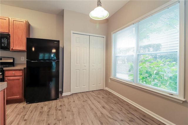 kitchen featuring black appliances, pendant lighting, and light hardwood / wood-style floors