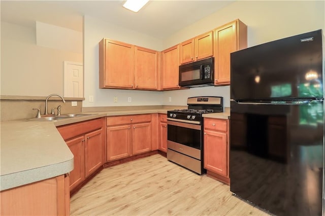 kitchen featuring light brown cabinets, black appliances, sink, light hardwood / wood-style floors, and kitchen peninsula