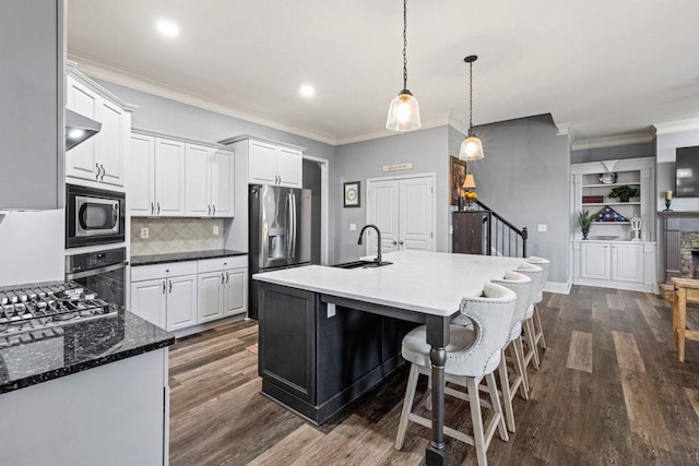 kitchen featuring tasteful backsplash, dark hardwood / wood-style floors, appliances with stainless steel finishes, an island with sink, and white cabinets