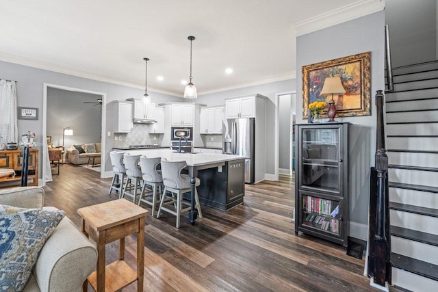 kitchen with stainless steel appliances, decorative backsplash, decorative light fixtures, white cabinets, and a center island