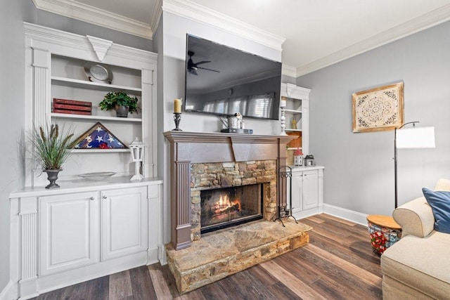 living room featuring ceiling fan, dark wood-type flooring, crown molding, and a stone fireplace