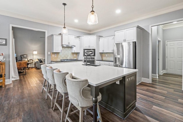 kitchen with pendant lighting, appliances with stainless steel finishes, white cabinetry, tasteful backsplash, and sink