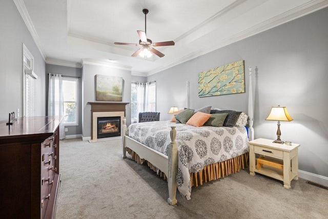 carpeted bedroom with ceiling fan, crown molding, and a raised ceiling