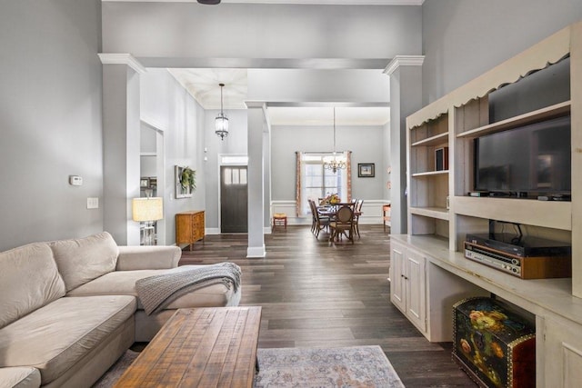 living room with dark hardwood / wood-style flooring, a chandelier, and decorative columns