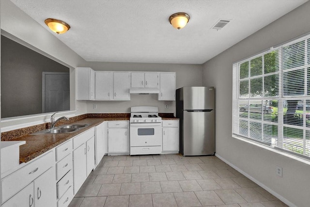 1234 Wellhouse Walk, Stone Mountain, GA 30088 - kitchen featuring freestanding refrigerator, white range with gas stovetop, under cabinet range hood, dark countertops, and white cabinetry