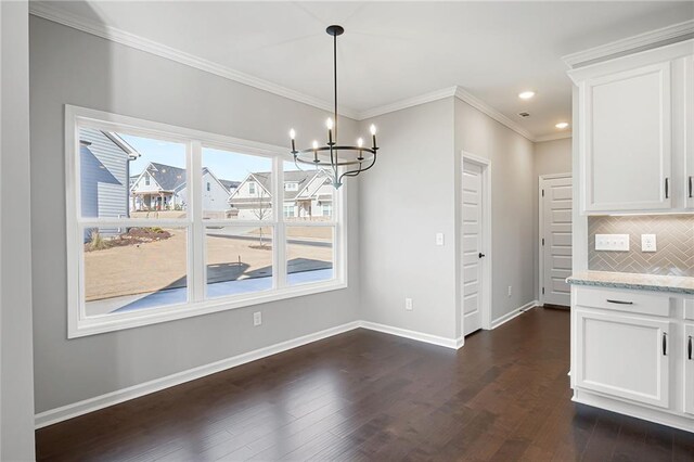 unfurnished dining area featuring dark hardwood / wood-style flooring, crown molding, and a chandelier