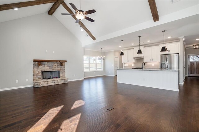 unfurnished living room with ceiling fan with notable chandelier, high vaulted ceiling, dark hardwood / wood-style floors, and beamed ceiling