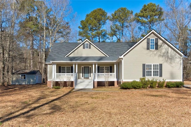 view of front of home with a porch, a shed, and a front lawn