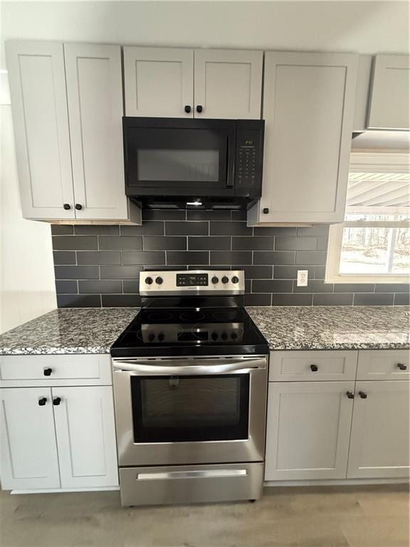 kitchen with electric stove, light stone countertops, decorative backsplash, and white cabinets