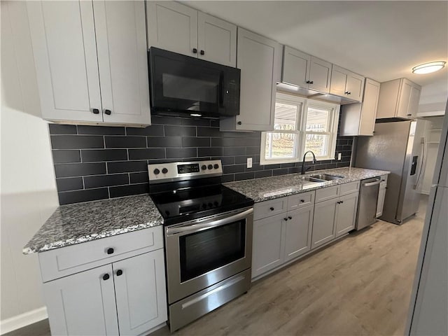 kitchen with sink, decorative backsplash, light stone counters, stainless steel appliances, and light hardwood / wood-style flooring