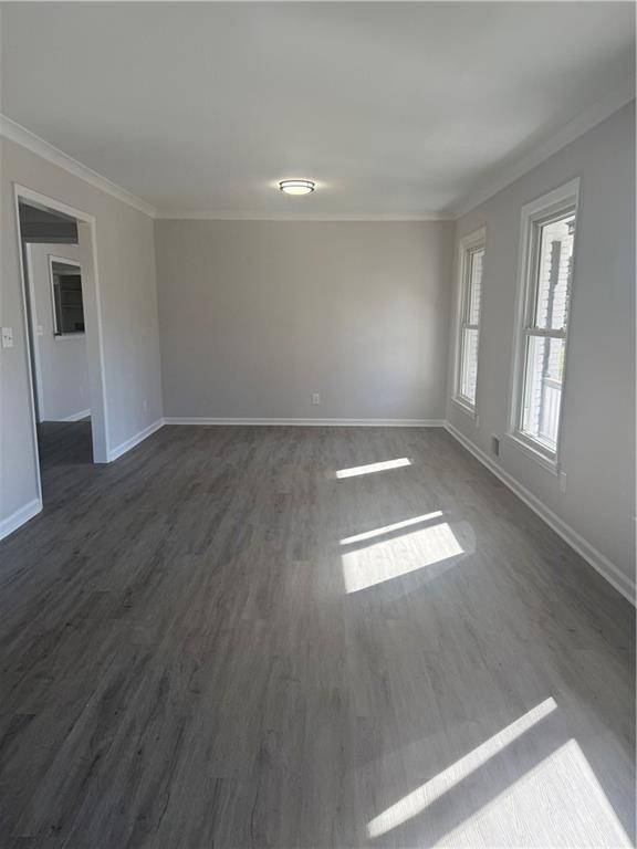 empty room with dark wood-type flooring and ornamental molding