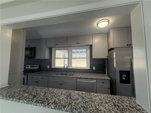 kitchen featuring stainless steel appliances, sink, light stone counters, and decorative backsplash