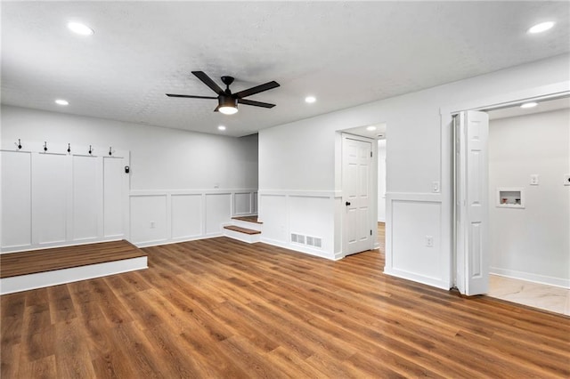 1150 Rankin St Unit 6H, Stone Mountain, GA 30083 - empty room featuring a ceiling fan, wood finished floors, recessed lighting, a wainscoted wall, and a decorative wall