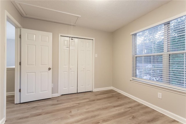 7113 Ambercrest Ct, Austell, GA 30168 - unfurnished bedroom featuring attic access, light wood-style flooring, baseboards, a closet, and a textured ceiling