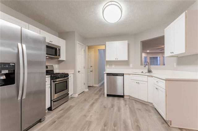 7113 Ambercrest Ct, Austell, GA 30168 - kitchen featuring appliances with stainless steel finishes, a sink, light wood-type flooring, white cabinets, and light countertops