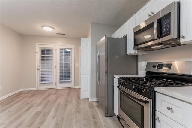 7113 Ambercrest Ct, Austell, GA 30168 - kitchen with appliances with stainless steel finishes, light wood-type flooring, white cabinets, light countertops, and a textured ceiling