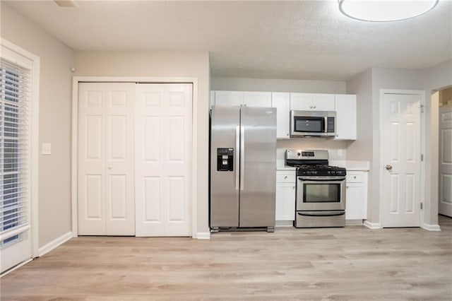 7113 Ambercrest Ct, Austell, GA 30168 - kitchen with appliances with stainless steel finishes, white cabinets, light wood-type flooring, light countertops, and a textured ceiling