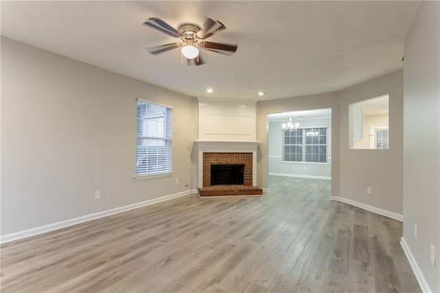 7113 Ambercrest Ct, Austell, GA 30168 - unfurnished living room with a chandelier, a ceiling fan, light wood finished floors, baseboards, and a brick fireplace