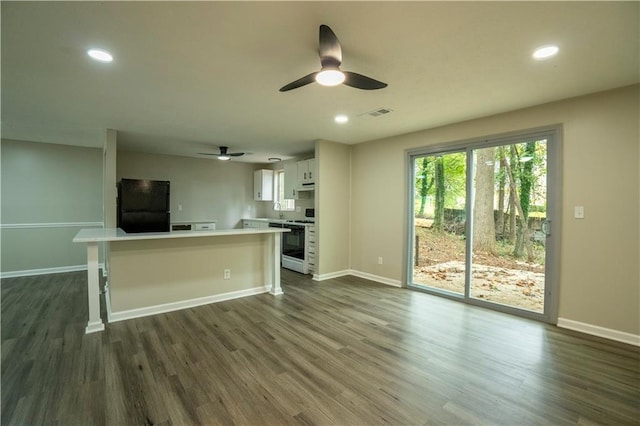 kitchen with black fridge, dark hardwood / wood-style flooring, white range with gas stovetop, white cabinets, and ceiling fan