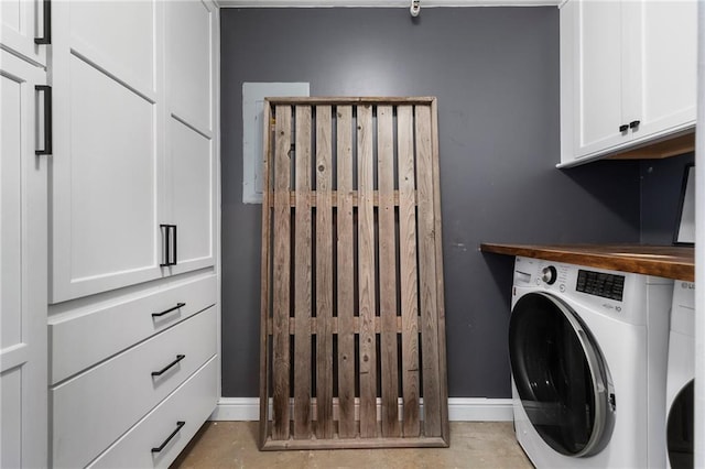 clothes washing area featuring baseboards, cabinet space, and washing machine and dryer