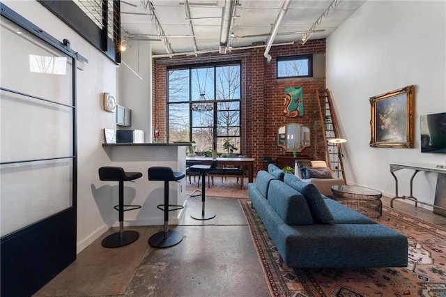 interior space featuring brick wall, finished concrete flooring, rail lighting, and baseboards