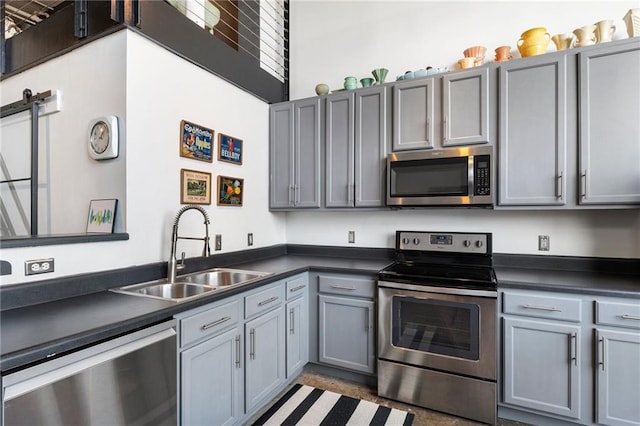 kitchen featuring a sink, dark countertops, gray cabinets, and stainless steel appliances