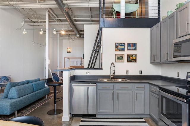 kitchen featuring dark countertops, appliances with stainless steel finishes, gray cabinetry, and a sink