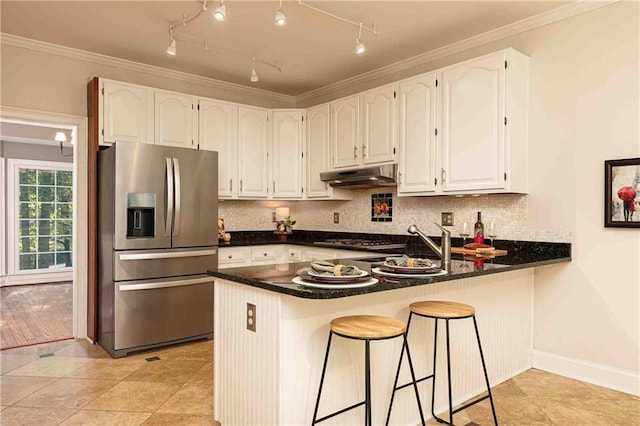 kitchen featuring appliances with stainless steel finishes, under cabinet range hood, a peninsula, white cabinetry, and dark countertops