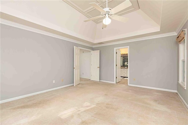 unfurnished bedroom with a raised ceiling, light colored carpet, ornamental molding, baseboards, and a ceiling fan