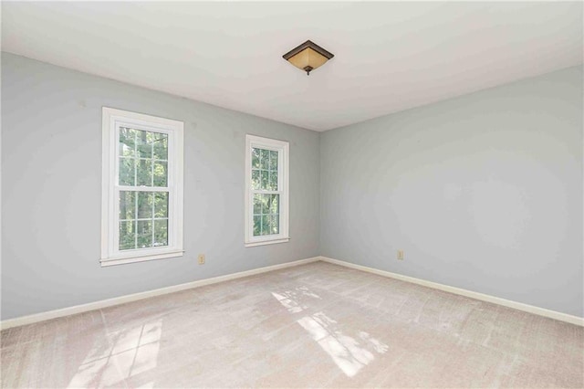 spare room featuring light carpet and baseboards