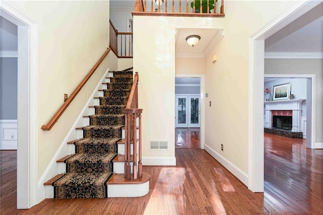 stairs featuring wood finished floors, crown molding, a premium fireplace, and baseboards