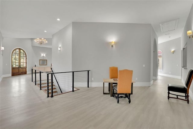 interior space featuring french doors, light wood-type flooring, and an inviting chandelier