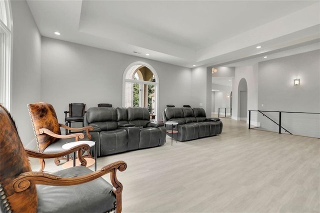 living room featuring a raised ceiling and light wood-type flooring