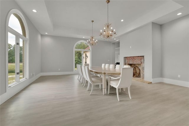 dining room featuring a raised ceiling, light wood-type flooring, and a chandelier