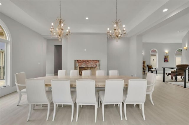 dining area featuring a fireplace, light hardwood / wood-style floors, and a chandelier