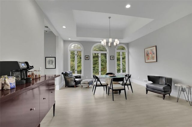 dining space featuring a chandelier, a tray ceiling, and light hardwood / wood-style flooring