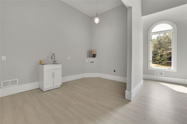 laundry area with sink, cabinets, and light wood-type flooring