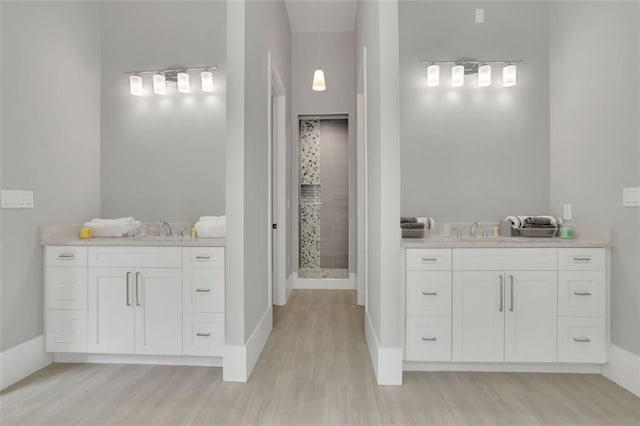 bathroom with tiled shower, vanity, and hardwood / wood-style flooring