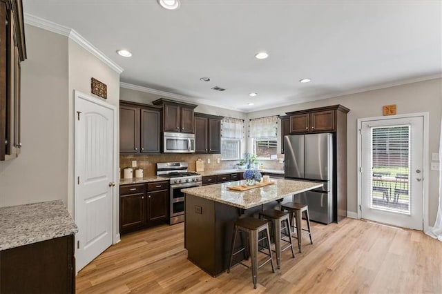 4275 Hunters Walk Way, Cumming, GA 30028 - kitchen featuring stainless steel appliances, dark brown cabinets, a breakfast bar, light wood finished floors, and crown molding