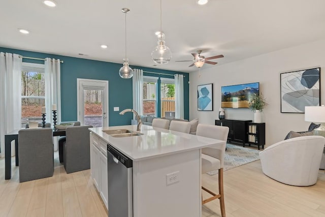 kitchen with open floor plan, a sink, dishwasher, light wood finished floors, and recessed lighting