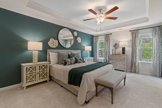 carpeted bedroom featuring a raised ceiling, baseboards, and ceiling fan